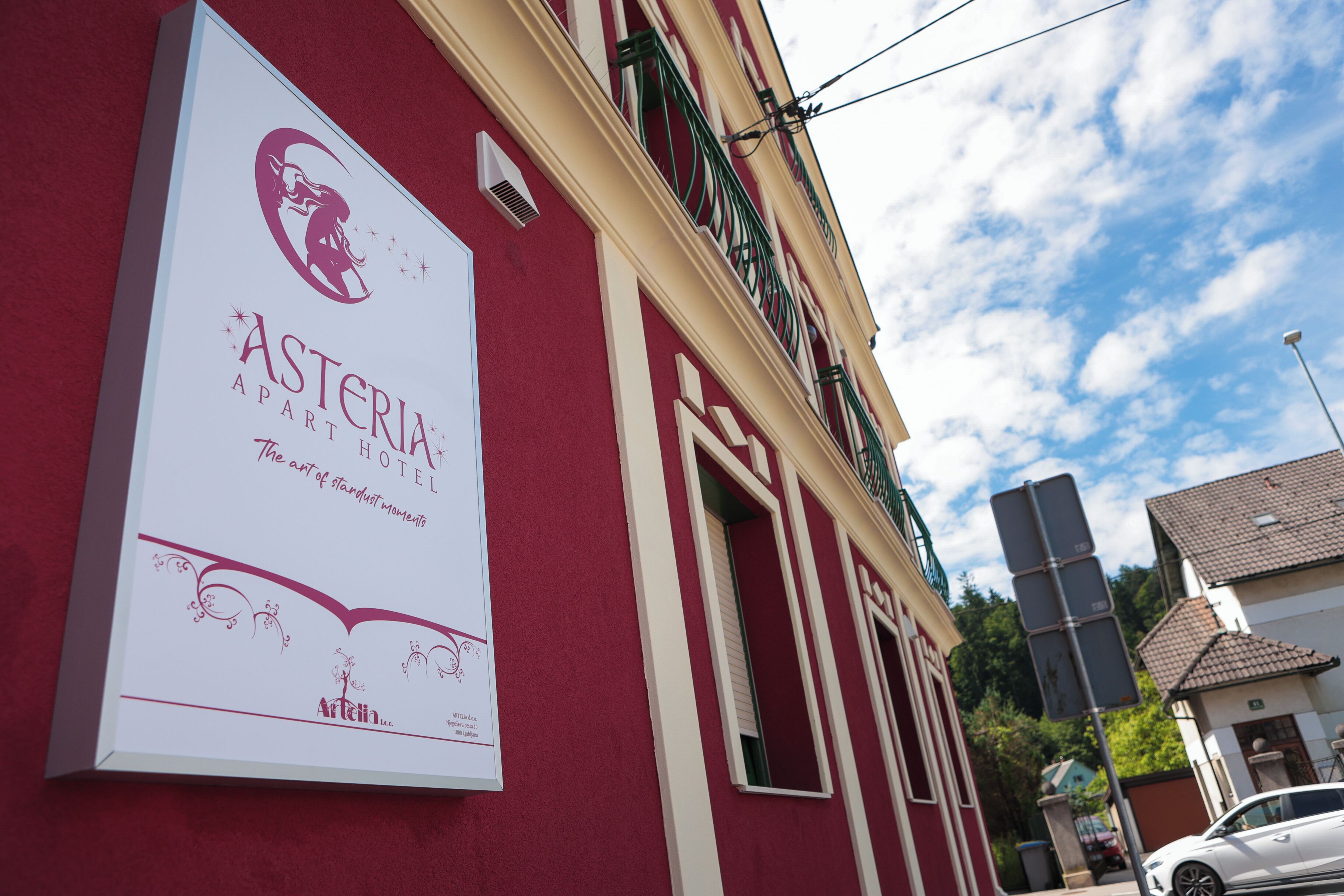Segnale per l'Asteria Apartment Hotel, con logo e testo che descrive l'arte di vivere sospesi nel tempo.