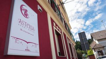 Segnale per l'Asteria Apartment Hotel, con logo e testo che descrive l'arte di vivere sospesi nel tempo.