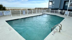 A rectangular pool with a white fence, no lifeguard on duty, and shallow water warning.