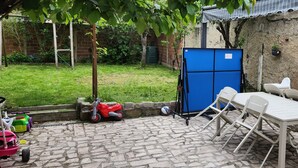 A patio area with a table and chairs, a blue storage unit, and a red toy car. - Studio Dépendance Quartier Tres Calme Proche de Paris (Les Pavillons-sous-Bois)