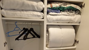 A closet with shelves holding folded clothes, a vacuum cleaner, and hangers. - Studio Dépendance Quartier Tres Calme Proche de Paris (Les Pavillons-sous-Bois)