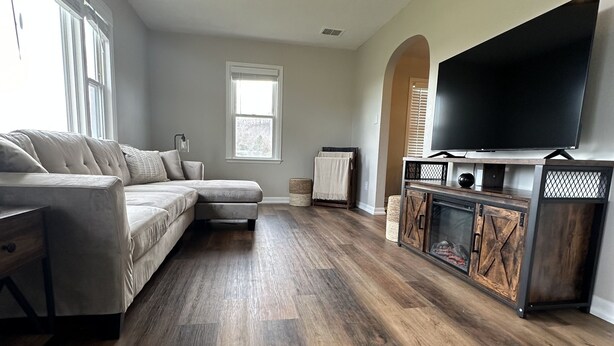 Een moderne woonkamer met een hoekbank, een flatscreen televisie en een houten tv-meubel.
