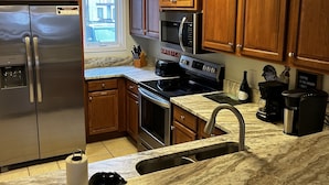 A kitchen with wooden cabinets, stainless steel appliances, a marble countertop, and a view of the outside. - Riverfront AlpineRiverBear, Sleeps10, Walk To Oktoberfest! 2 HotTubs, HomeCinema (Helen)