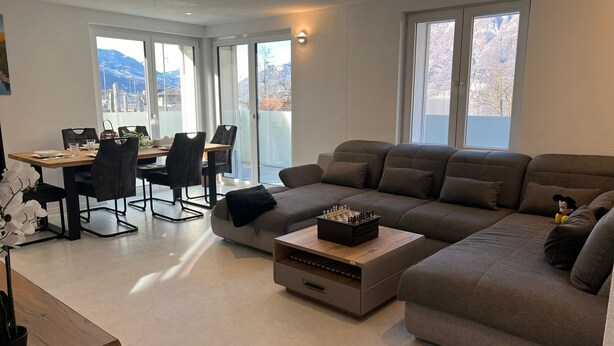 A modern living room with a sofa, a coffee table, and a dining area with chairs and a table. - Ferienwohnung am Schönen Walensee in der Nähe der Gondelbahn Flumserberg (Unterterzen)