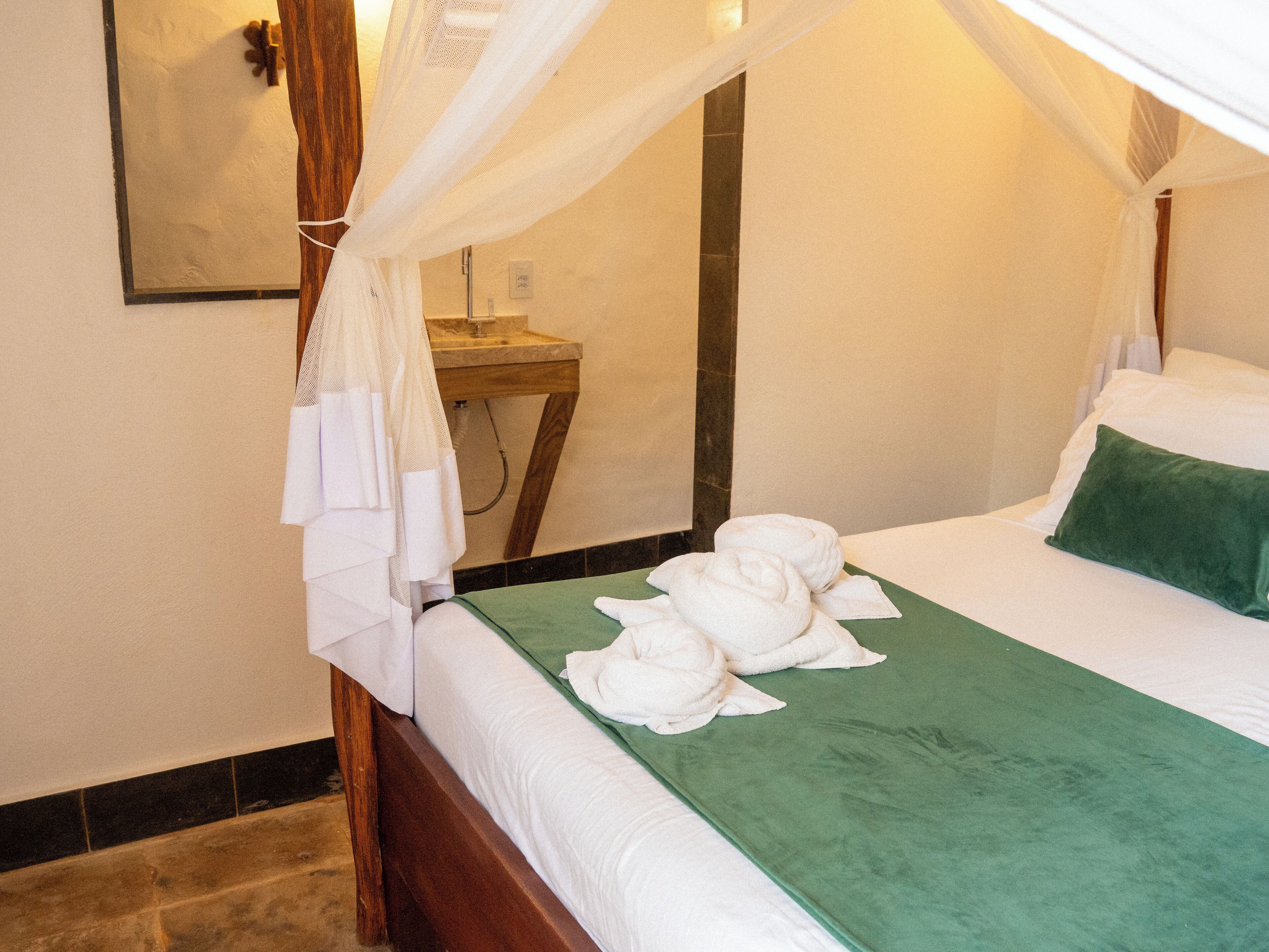 A neatly made bed with a green bedspread, white pillows, and a green throw blanket.