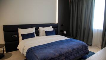 Habitación de hotel moderna con una cama grande, una mesita de noche y vistas al exterior.