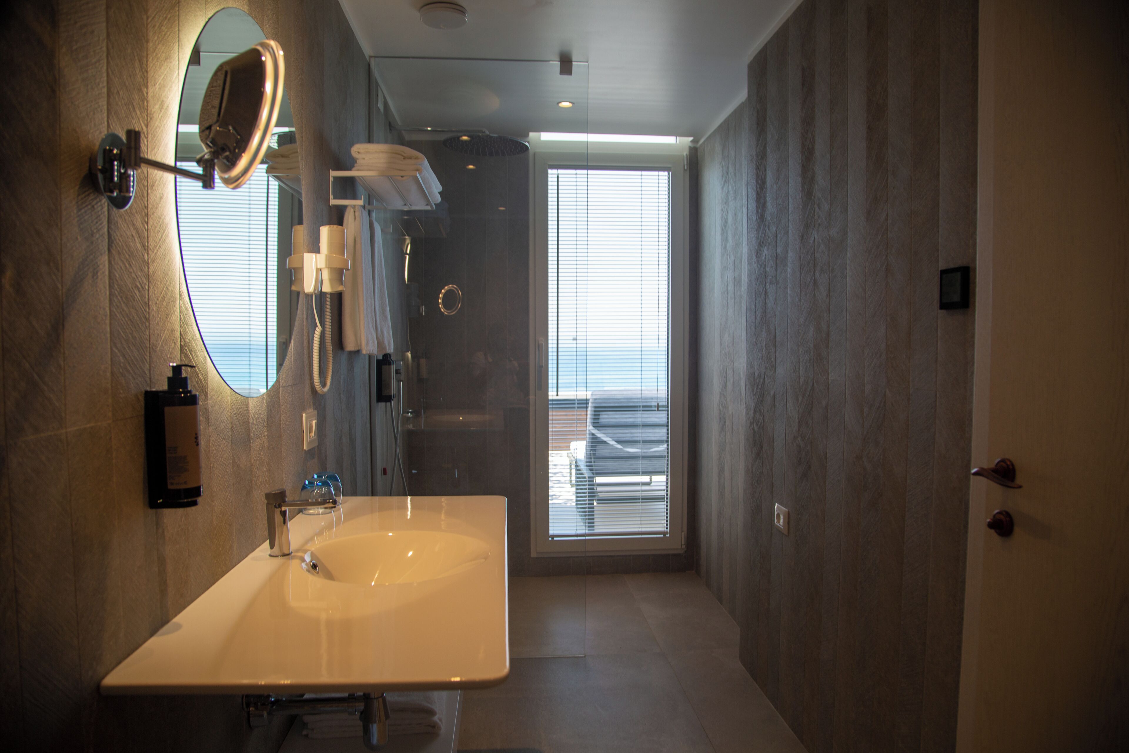 Une salle de bain moderne avec un grand miroir, un lavabo et un espace douche.