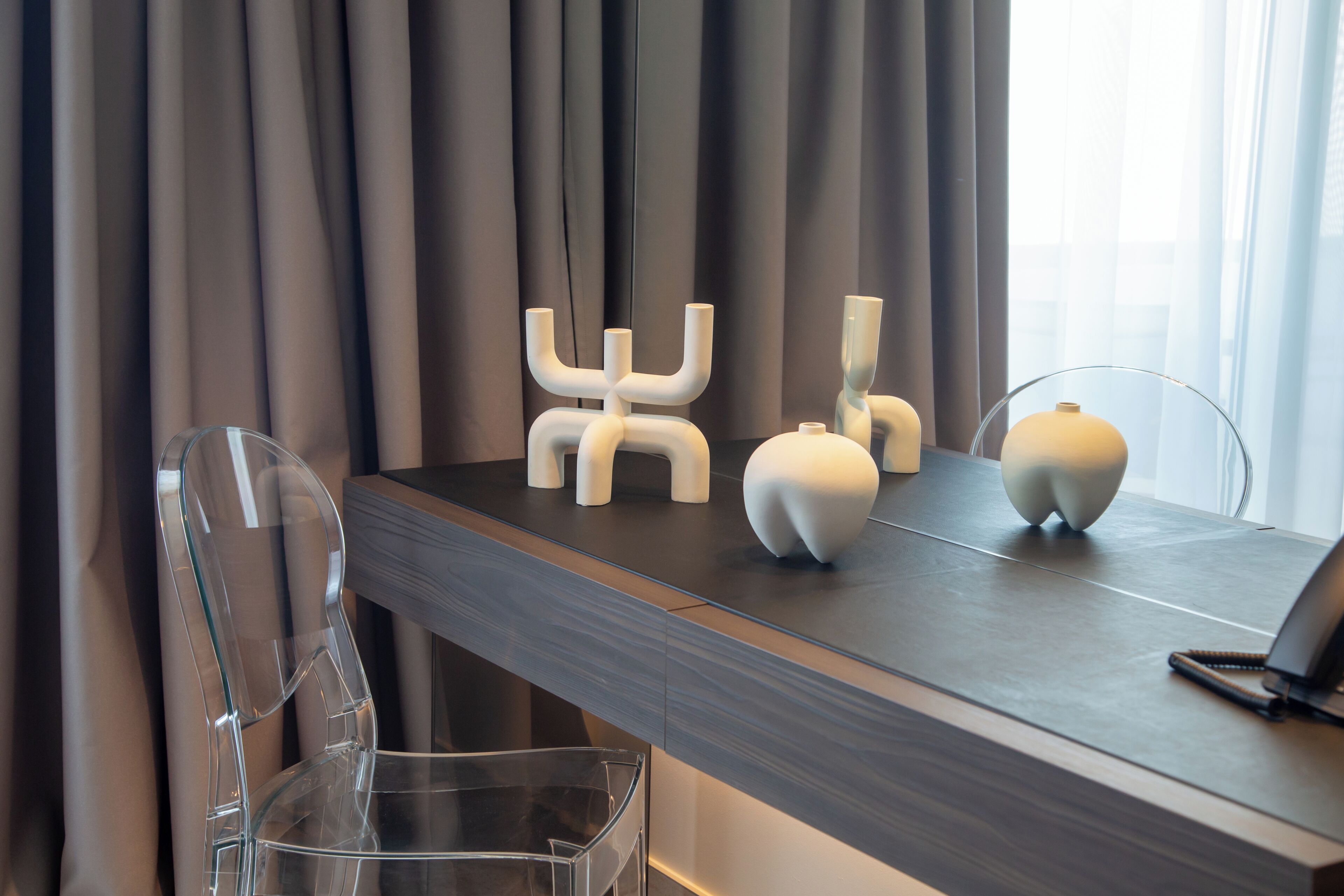 A modern dining area with a dark wooden table, clear glass chairs, and minimalist white decor.