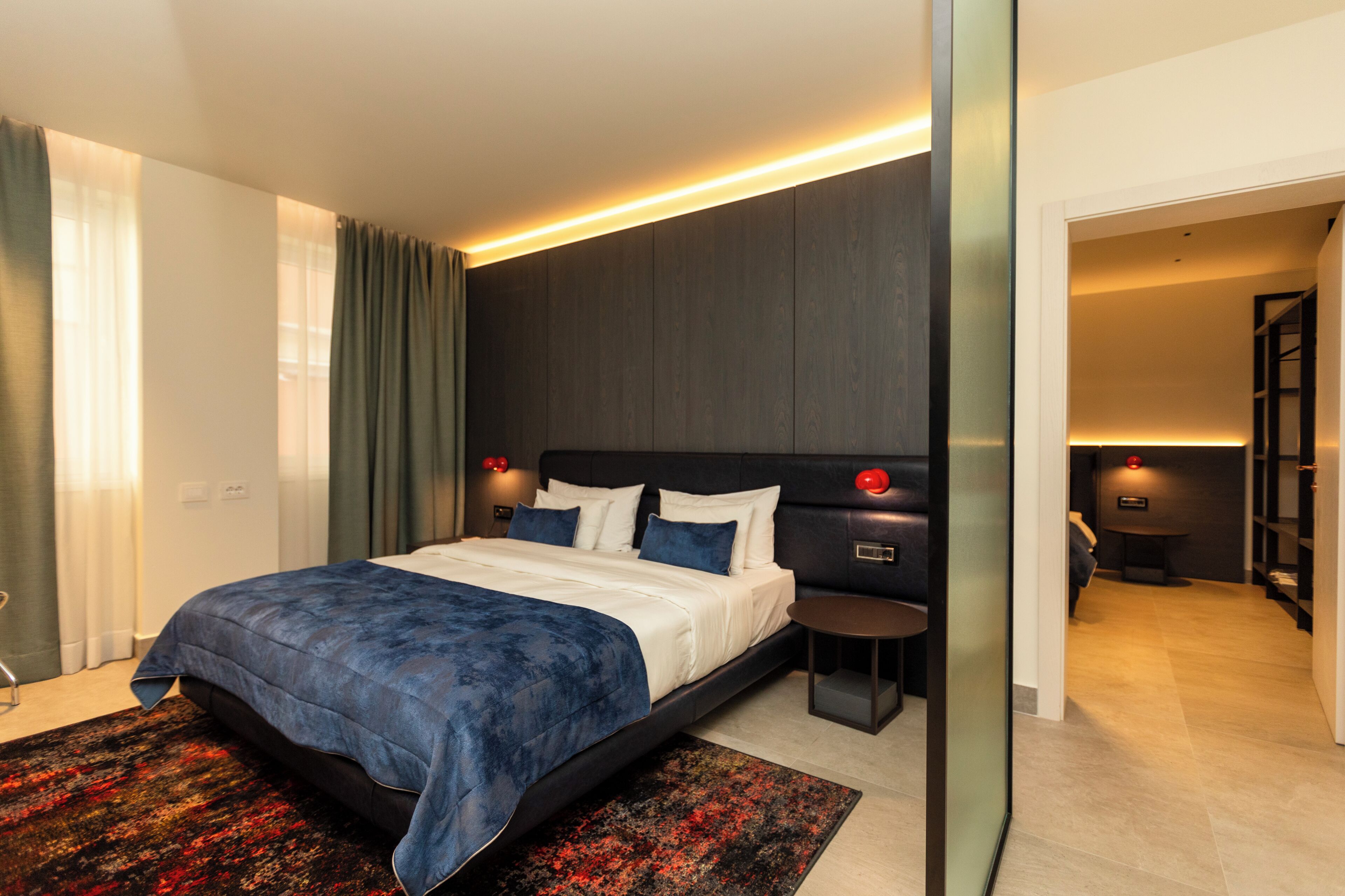 A modern hotel room with a large bed, a bedside table, and a built-in wardrobe.