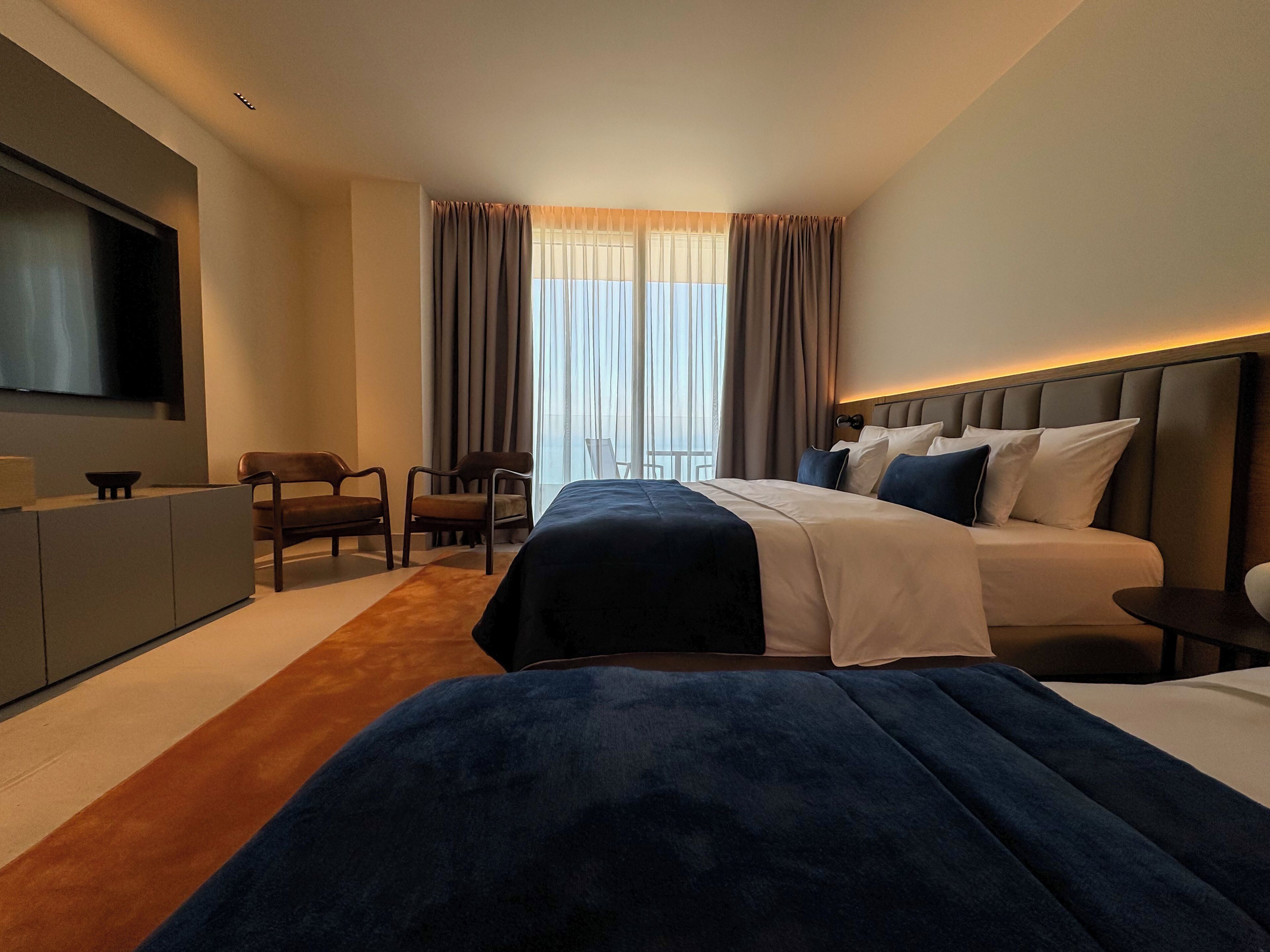 Une chambre d’hôtel avec un lit, une télévision, un bureau et une chaise.