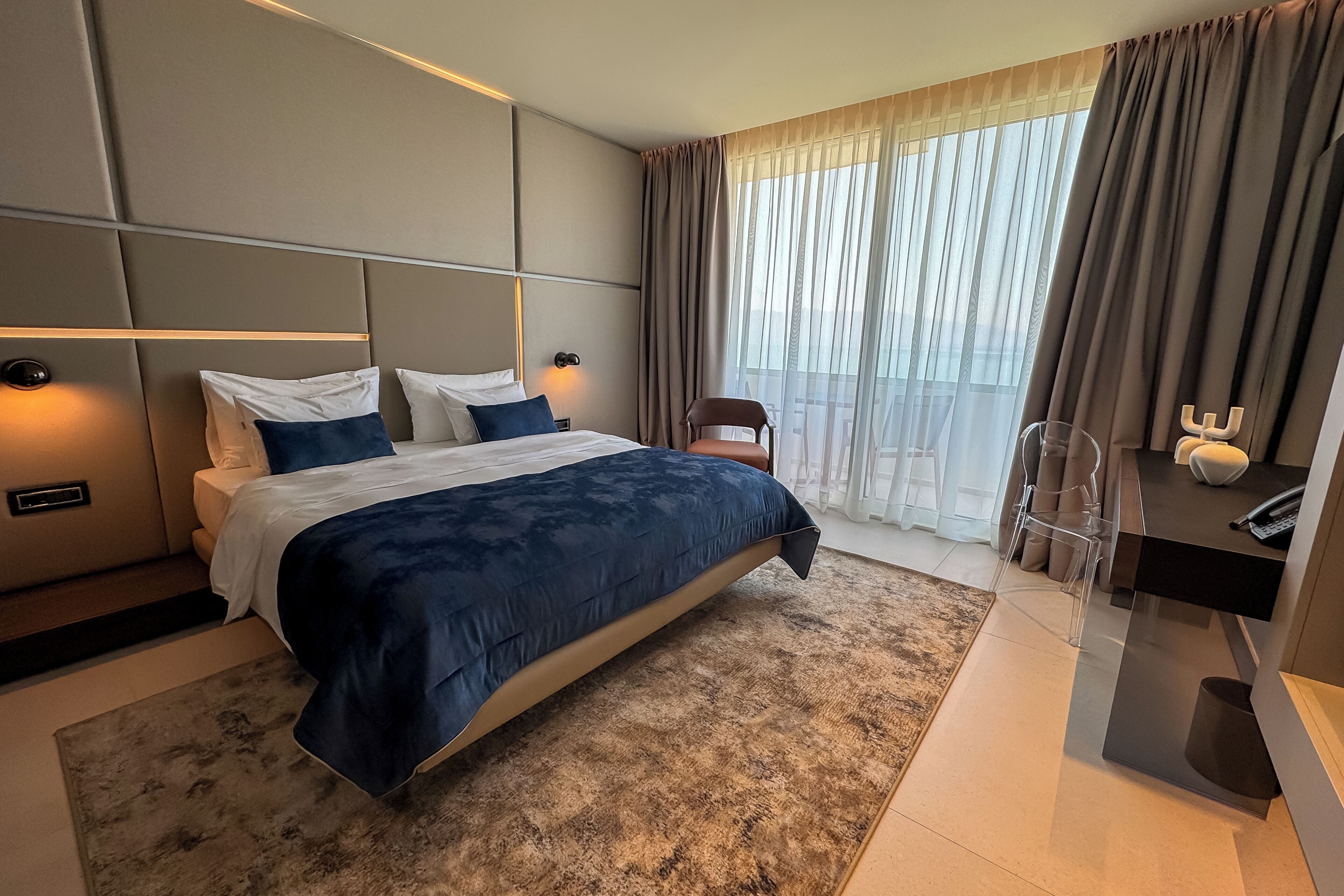 Un dormitorio moderno con una cama grande, un escritorio y una silla.