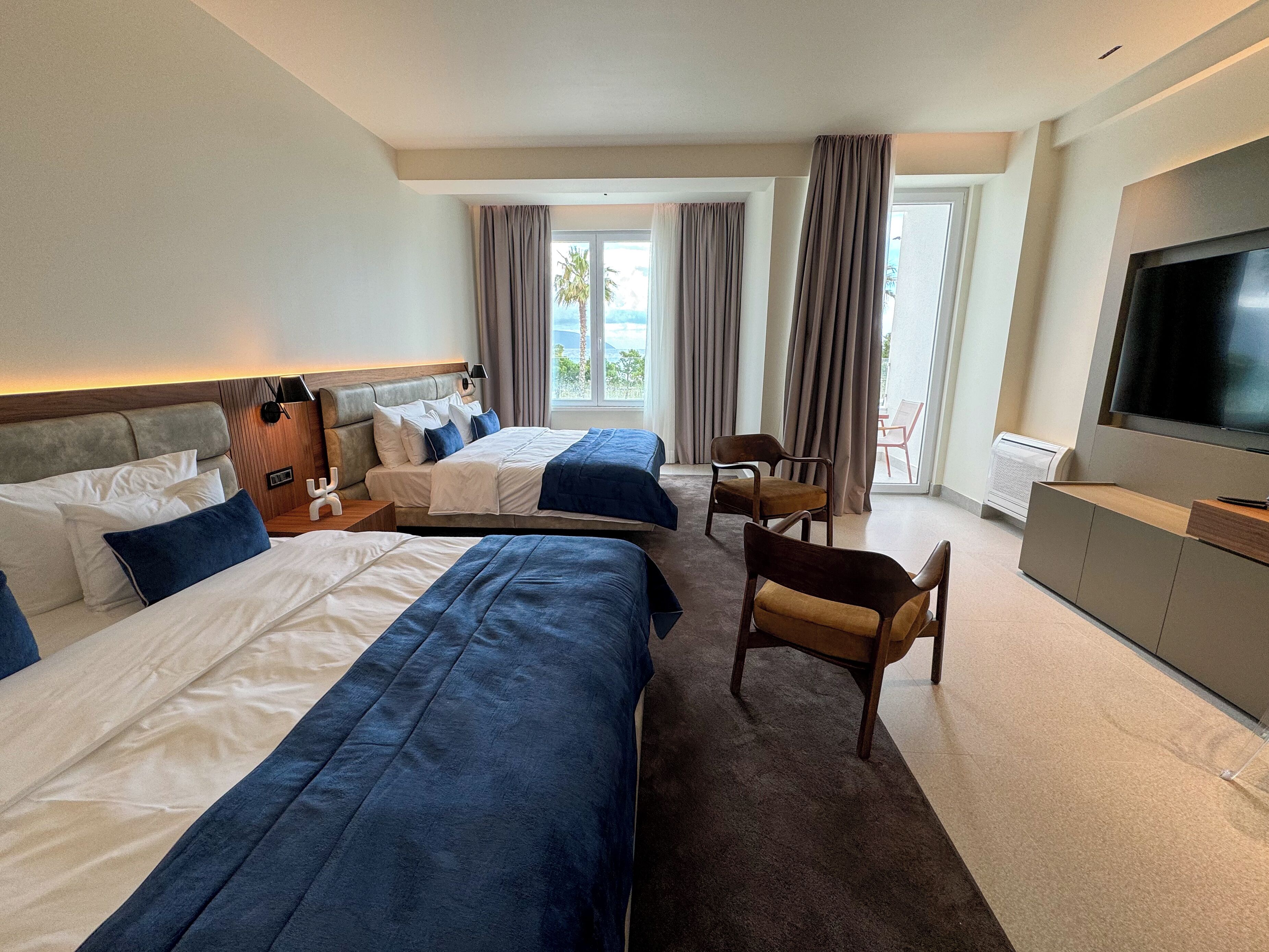 A hotel room with two beds, a TV, a desk, and a chair.