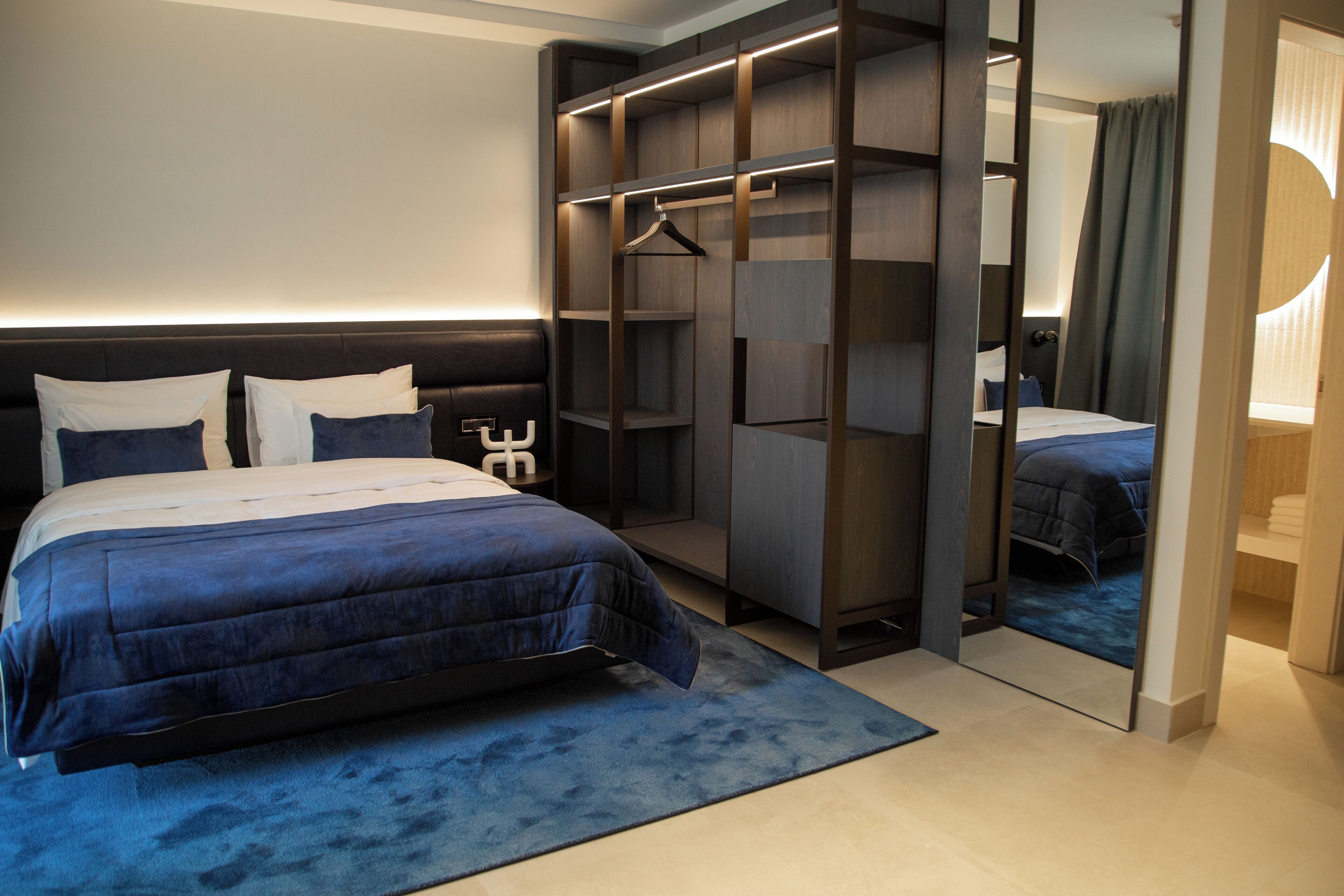 Une chambre d’hôtel moderne avec un grand lit, une armoire et un miroir.