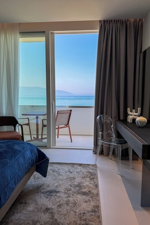A hotel room with a bed, a desk, a chair, and a view of the sea. - Abi's Hotel & SPA Vlore (Vlorë)