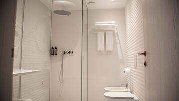 Een moderne badkamer met een douche met glazen wand, toilet en wastafel.