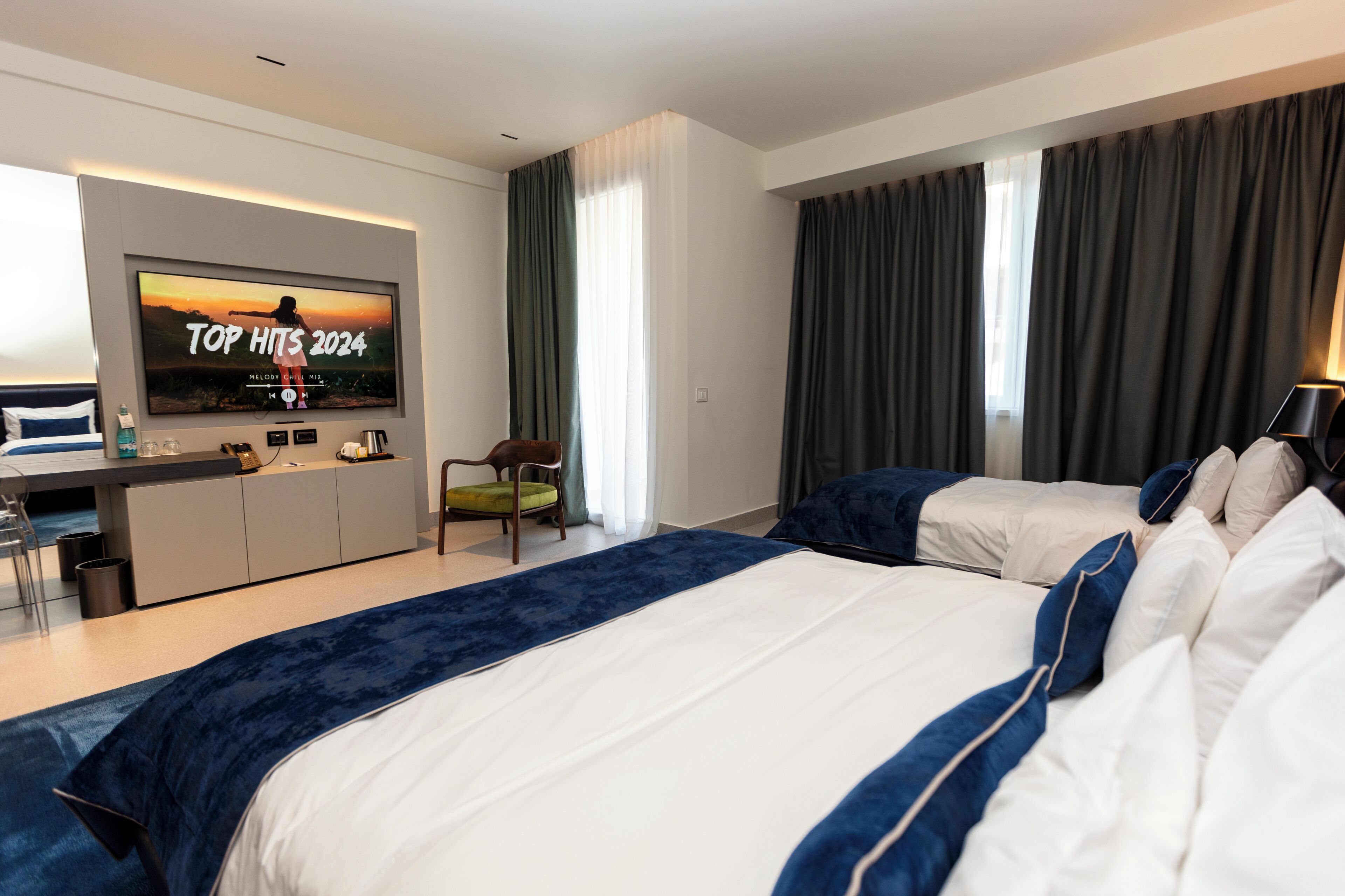 Une chambre d’hôtel dotée d’un grand lit, d’un bureau avec un téléviseur à écran plat, d’une chaise et offrant une vue sur l’extérieur par les fenêtres.