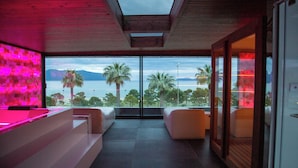 Un intérieur moderne avec une grande baie vitrée donnant sur des palmiers et des montagnes.