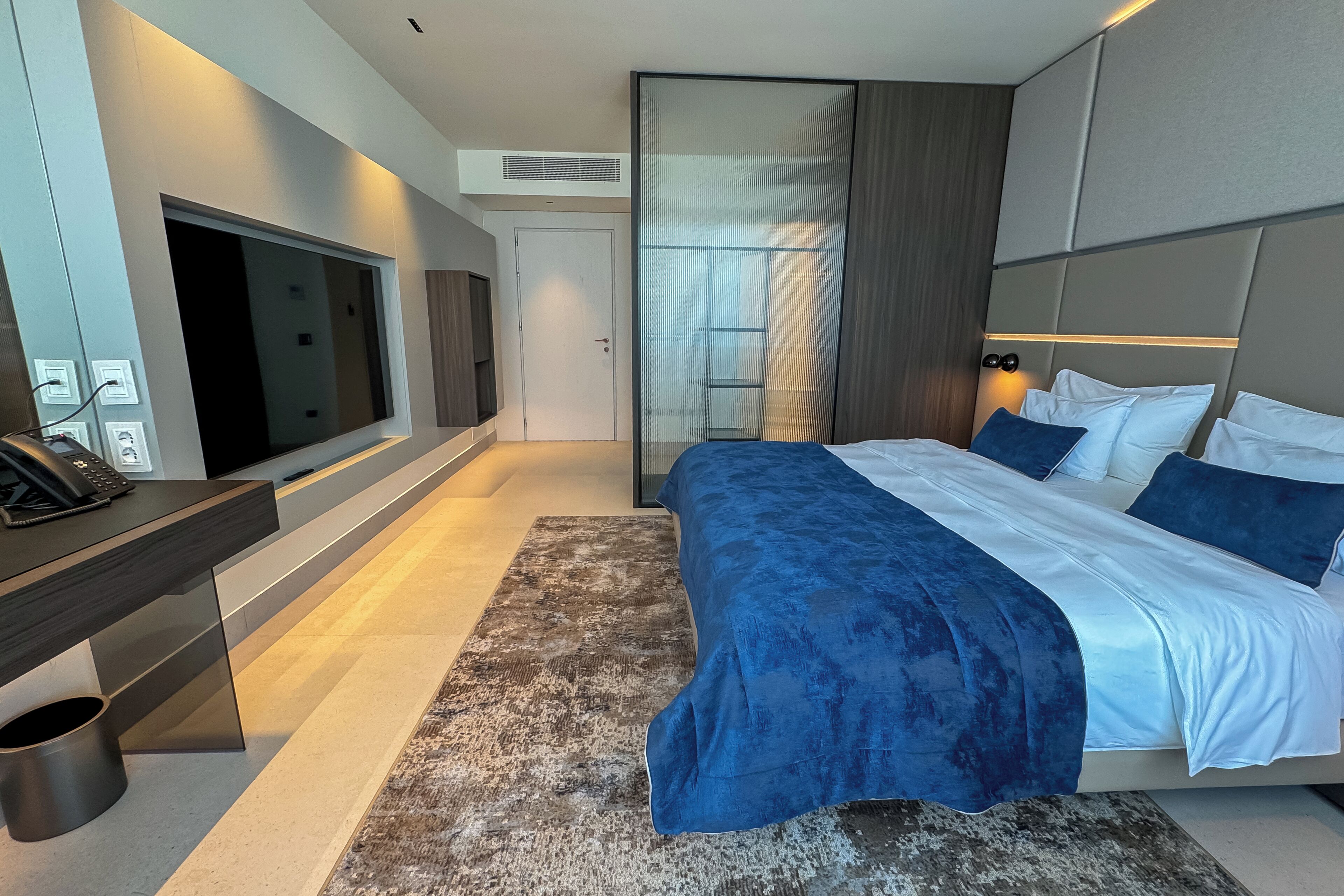 Une chambre d’hôtel moderne dotée d’un grand lit, d’une télévision à écran plat, d’un bureau et d’une armoire.