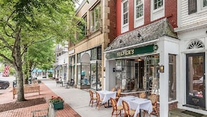A street with outdoor seating, a restaurant named 'SILVER'S' with a green awning, and brick buildings.