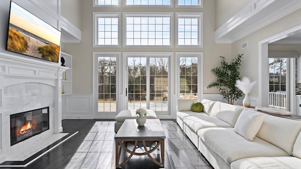 A spacious living room with a fireplace, large windows, a sofa, and a coffee table.