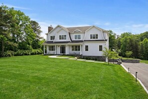 Une maison à deux étages avec un porche à l’avant, une allée et une pelouse bien entretenue.