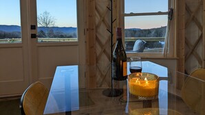 Un comedor con una mesa, sillas, una vela y una botella de vino.