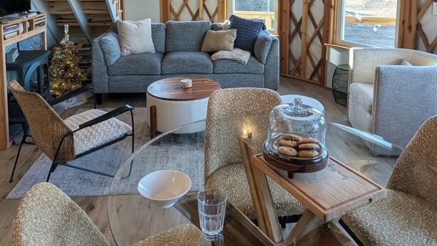 Un salón acogedor con un sofá gris, una escalera de madera y un árbol de Navidad.