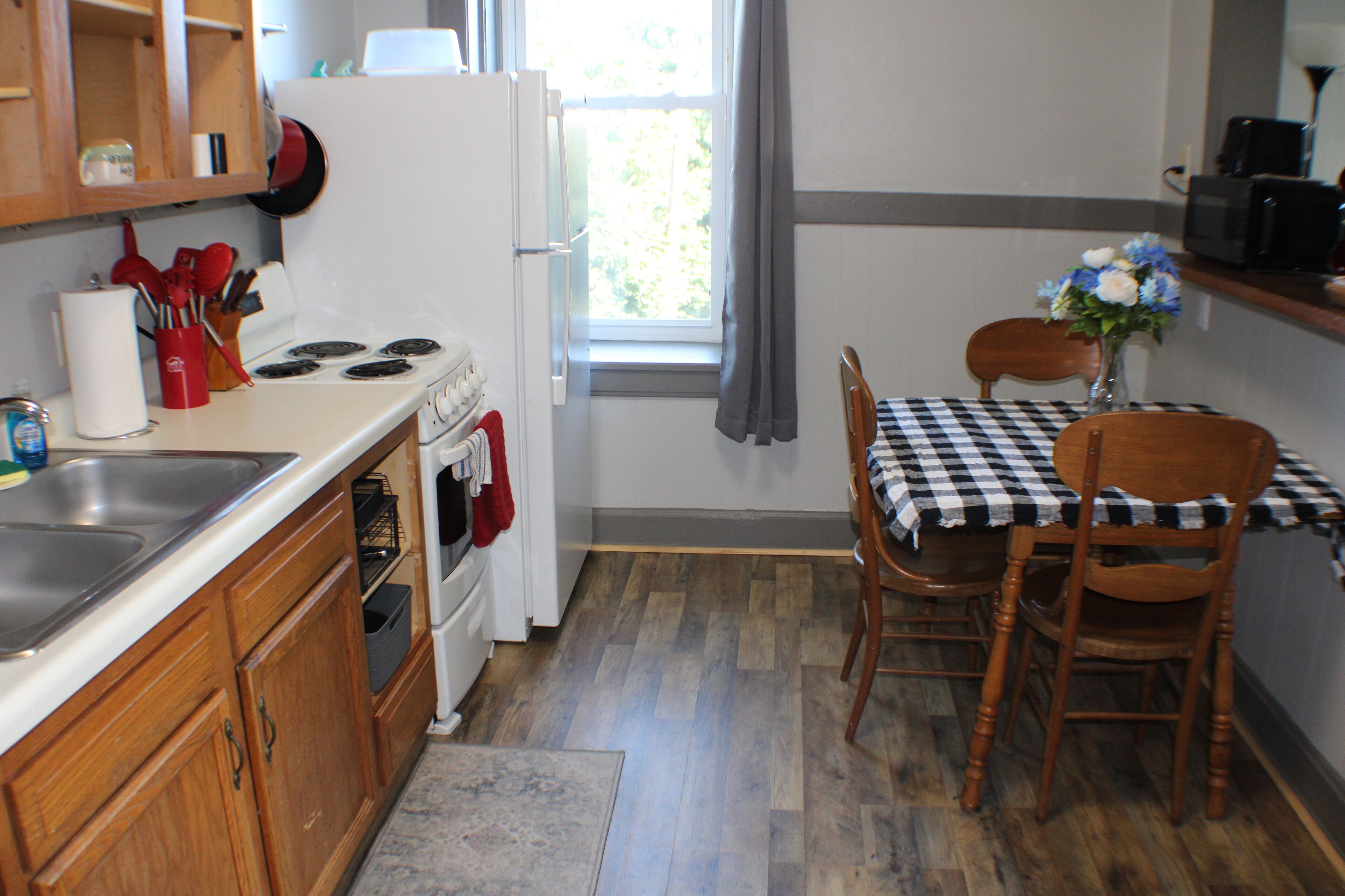 A kitchen with wooden cabinets, a stove, a sink, and a dining table with chairs.