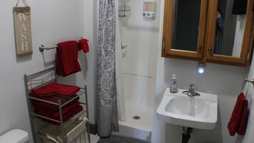 A bathroom with a shower, a sink, a towel rack, and a toilet.