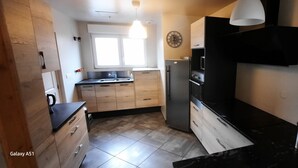 Cocina compacta con refrigerador, horno y microondas. Cuenta con una ventana que proporciona luz natural y un lavamanos.