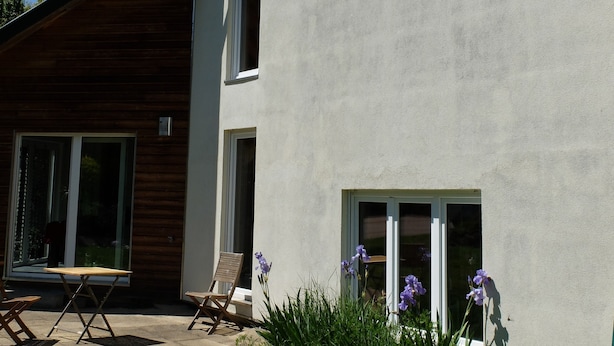 Una casa moderna con techo inclinado, ventanas amplias y un patio cubierto de césped.