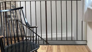 Une pièce avec un mur en pierre, une rambarde en métal noir et un plancher en bois.