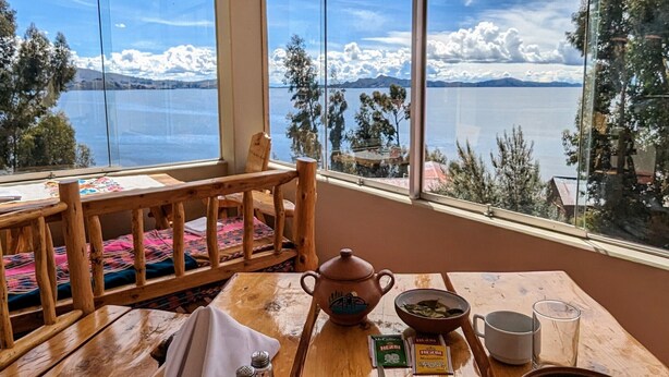 Una mesa de comedor con comida, saleros y pimenteros, una tetera y una taza.