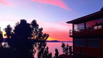 A building with a balcony overlooking a body of water and a sunset.