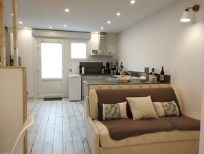 Cozy living space with a kitchenette, sofa, dining table, and bench.