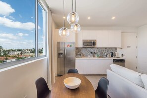 Enjoy meals with a city view from the kitchen's large window, featuring a refrigerator, microwave, and dishwasher.