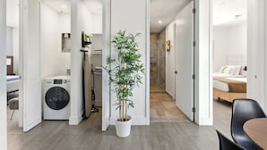 A modern hotel room with a washing machine, a potted plant, and a bed.