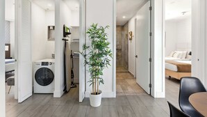 Une chambre d’hôtel moderne équipée d’une machine à laver, d’une plante en pot et d’un lit.