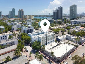 An aerial view of a cityscape with modern buildings, a clear sky, and a body of water in the background. - Elegant SoBe 2 Bedroom Apartment (Miami Beach)