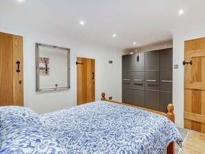 A bedroom with a bed, a wardrobe, a mirror, and a door.
