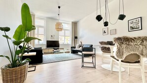 Ett modernt vardagsrum med en stor växt, en soffa, ett soffbord och en tv.
