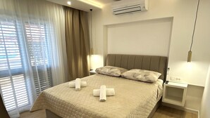 Habitación de hotel con cama, cortinas, aire acondicionado, lámparas de noche y mesitas de noche.
