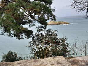 A coastal landscape with a rocky foreground, a body of water, and a distant island. - à 2 Minutes en Voiture du Port et de la Plage des Sables Blanc (Douarnenez)