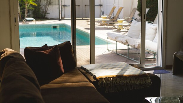 Una sala de estar con sofá, vista a una piscina y sillones de exterior.