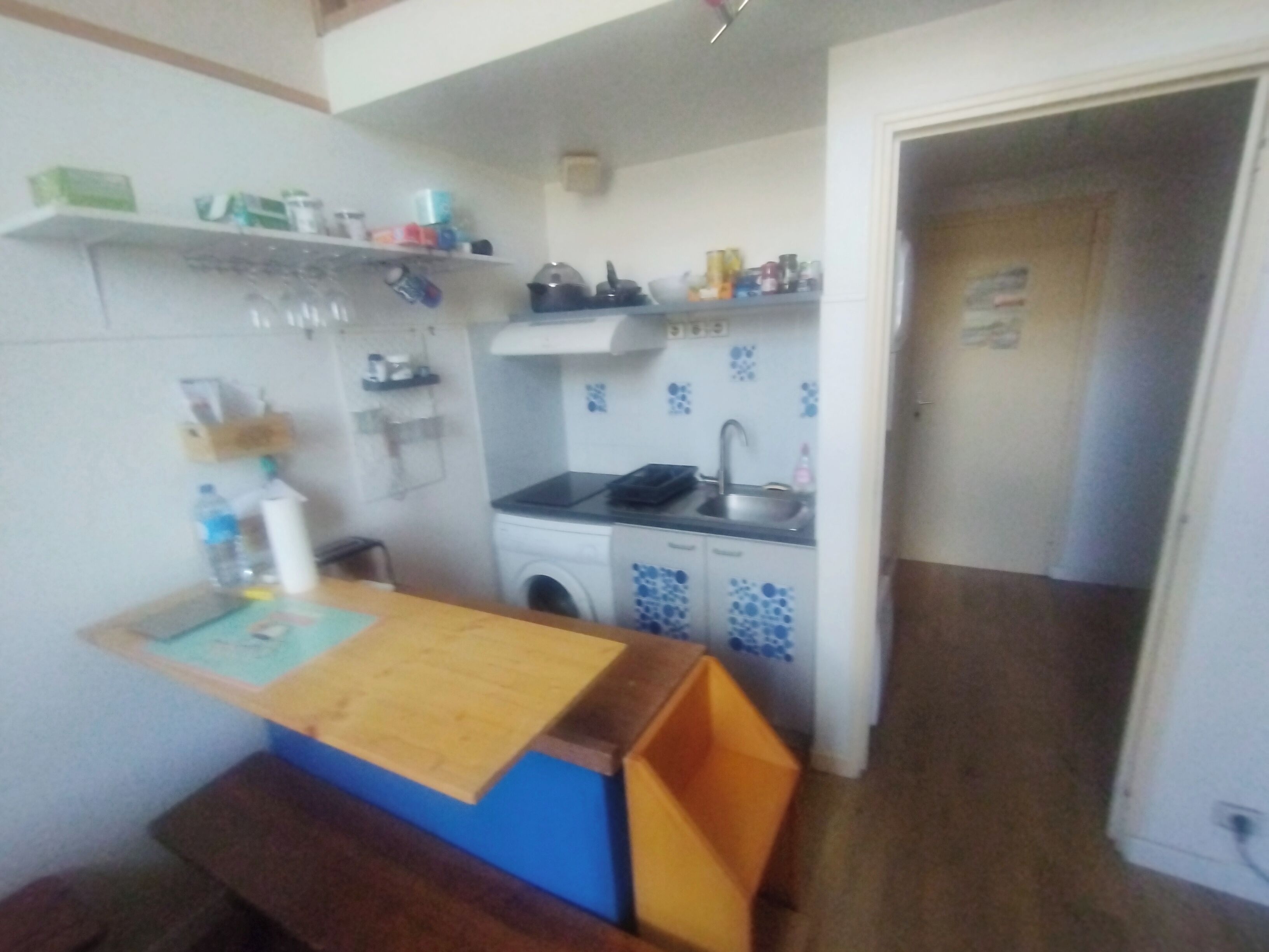 Een kleine keuken met een wasmachine, een spoelbak en een klein aanrecht.