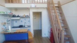 Eine kleine Küche mit Holztisch, einer eingebauten Bank und einer Treppe, die in einen oberen Bereich führt.
