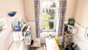 Ein Zimmer mit einem großen Fenster, einem kleinen Tisch mit Dekoration und einer Wand mit verschiedenen gerahmten Bildern.