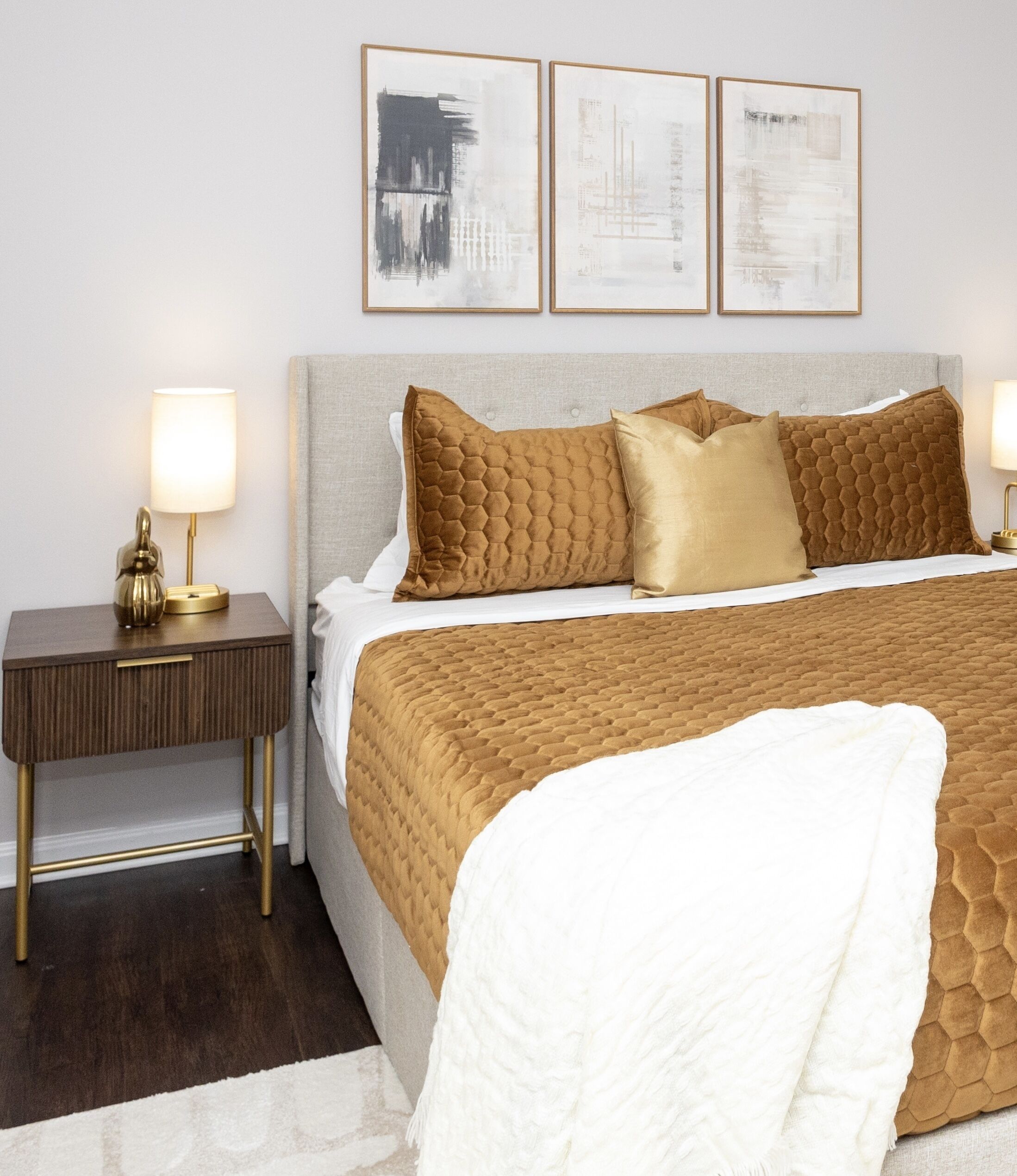 A neatly arranged bedroom with a bed, two bedside tables, and three framed artworks on the wall.