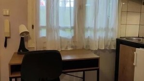 Een kleine keuken met een tafel, stoel en een raam met dunne gordijnen.