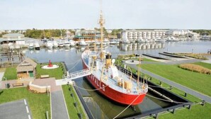 Ein großes Schiff liegt in einer Marina vor Anker, mit einer Brücke und einem kleinen Gebäude in der Nähe.